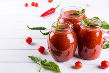 Spicy sweet tomato sauce with garlic, pepper and herbs in a glass jars.