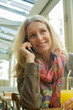 © PhotoAlto - Mature woman talking on cell phone and smiling in cafe