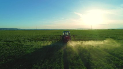 Fototapete - Aerial view of farming tractor plowing and spraying on field