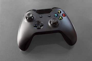 Top view of a logo free, black videogame controller on grey background