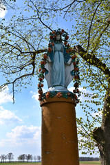 The Virgin Mary old rural roadside shrine in flowers and blue robe