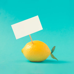 Lemon on pastel blue background with white paper card note. Minimal summer concept. Flat lay.