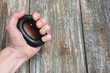 Man is holding in hand the hand grip strengthener. Expander on the wooden background. Sporty wrist builder for everyday trainings.
