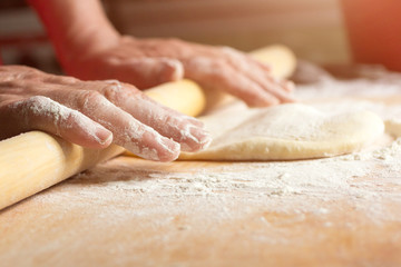 Woman rolls the dough with a rolling pin