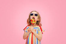 Trendy Little Model Wearing Multicolored Striped Dress With Sunglasses And Licking Swirl Lollipop.