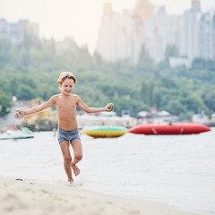 Wall Mural - Happy cheerful boy running along sandy beach, image with square aspect ratio