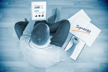 Poster - The word synergy and business graphs against young creative businessman looking at tablet