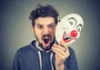 angry screaming man holding a clown mask