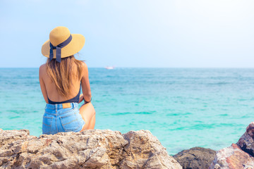 Wall Mural - beautiful women with hat looking to the ocean in Thailand , beach vacations