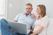 © WavebreakmediaMicro - Relaxed couple using laptop on sofa