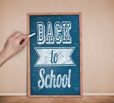 Hand writing with chalk against blackboard on wall
