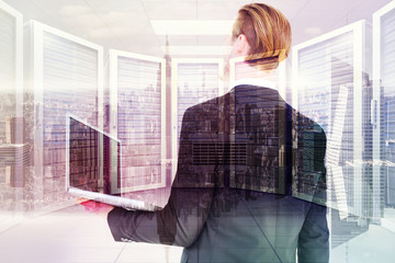 Poster - businessman looking up holding laptop against room with large window looking on city