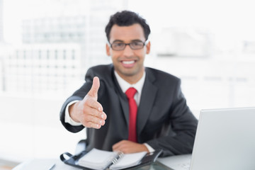 Poster - Blurred businessman offering a handshake at office desk