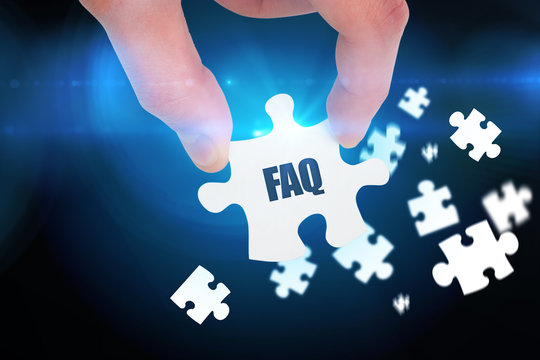 The word faq and hand holding jigsaw piece against blue background with vignette