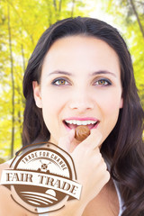 Wall Mural - Pretty brunette eating chocolate candy against trees in the autumnal forest