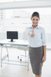 © WavebreakmediaMicro - Smiling businesswoman gesturing thumbs up at office