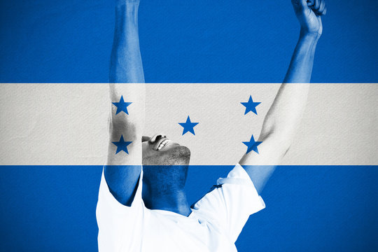 Excited handsome football fan cheering against honduras national flag