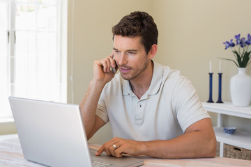 Man using laptop and mobile phone at home