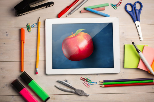 Composite image of digital tablet on students desk showing apple