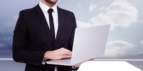 Poster - Mid section of a businessman using laptop against clouds in a room