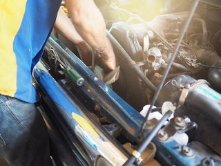 Automobile mechanic with tools in hands checking car engine in garage. Auto repair service.