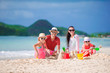 © travnikovstudio - Family of four making sand castle at tropical white beach
