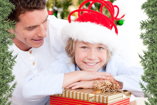 Handsome father celebrating christmas with his son against green fir branches