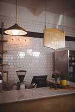 Text And Pendant Light Hanging Over Counter Against White Wall