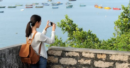 Canvas Print - Woman go hiking and taking photo of the sea view