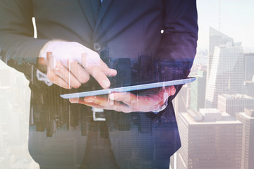 Wall Mural - Mid section of a businessman touching digital tablet against mirror image of city skyline