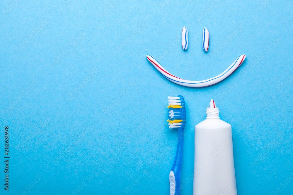 Tooth-paste in the form of face with a smile. Tube of the paste on blue ...