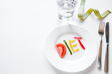 Wall Mural - diet concept dish with vegetables, cutlery and measuring tape with place for text on a white background