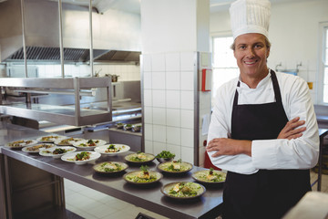 Portrait of happy chef with standing with arms crossed at order station