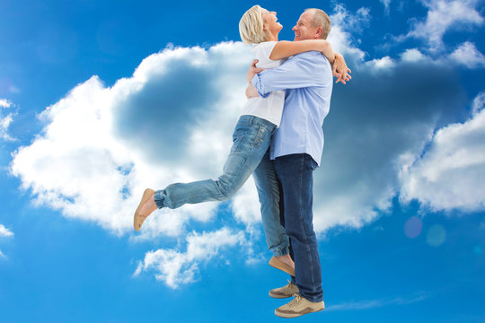 Mature couple hugging and having fun against cloudy sky