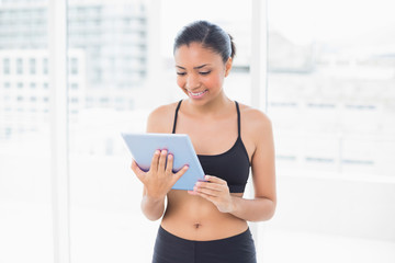 Poster - Concentrated dark haired model in sportswear using a tablet pc