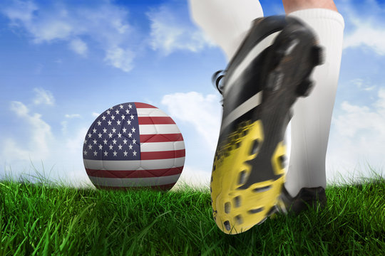 Composite image of football boot kicking usa ball against field of grass under blue sky