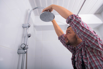 Workman repairing shower head in bathroom