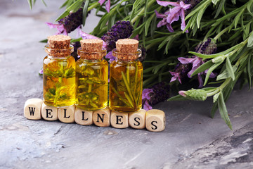 lavender oil in a glass bottle on a background of fresh flowers.