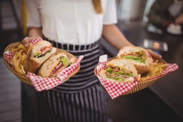 Midsection of waitress holding fresh fast food in wicker baskets