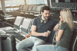 © Yakobchuk Olena - Outgoing bearded man drinking cup of coffee while telling with happy girl. Glad travelers communicating in waiting room concept