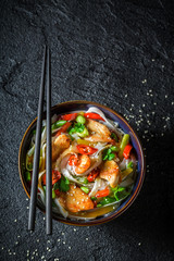 Hot noodle in dark bowl with chopsticks on black rock