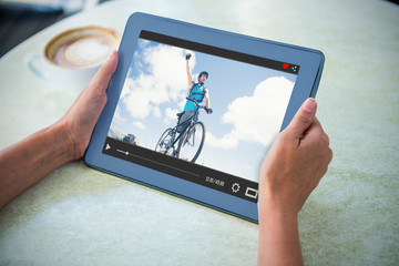 Poster - Fit man cycling on rocky terrain and cheering against person holding tablet computer at table in cafe