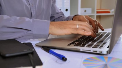 Poster - close up details married man working on laptop. fingers businessman entering data on computer. entrepreneur white desk with paper document different financial charts graphics and tables