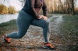 Overweight woman warming up before running in park