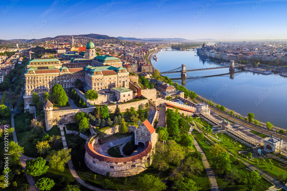 Budapest, Hungary - Aerial panoramic skyline view of Buda Castle Royal Palace with Szechenyi Chain Bridge, Hungarian Parliament and Matthias Church at sunrise with clear blue sky - obrazy, fototapety, plakaty 