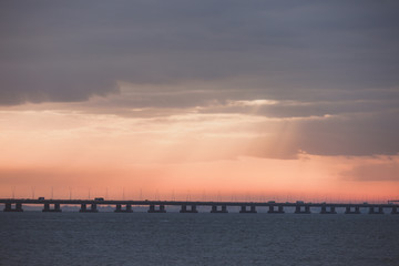 Wall Mural - Orange sunset over the bridge silhouette. Ocean hrizon sunny landscape