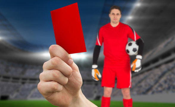 Composite image of hand holding up red card to goalie against football stadium
