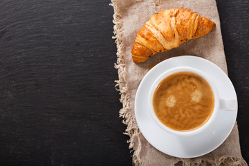 Wall Mural - cup of coffee and croissant on dark table