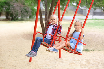 Wall Mural - Cute girls on swings at playground