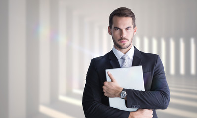 Sticker - Businessman in suit posing with his laptop  against curved white room